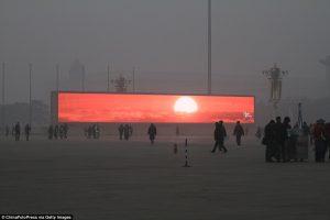 The LED screen shows the rising sun in Tiananmen Square which is shrouded with heavy smog.